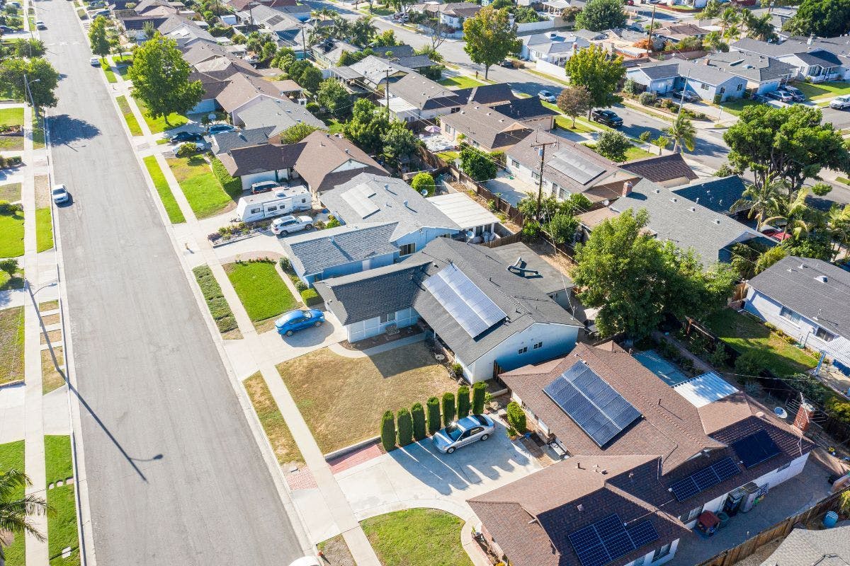An aerial view of a neighborhood showing houses with rooftop solar panels.