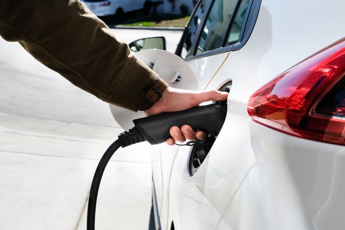 A person plugging an EV charger into a vehicle.