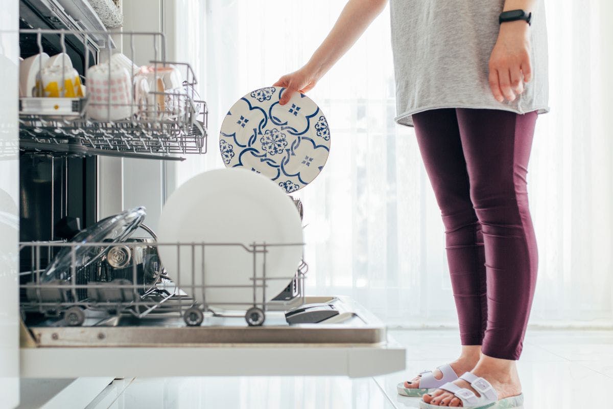 A person putting dishes into a dishwasher.