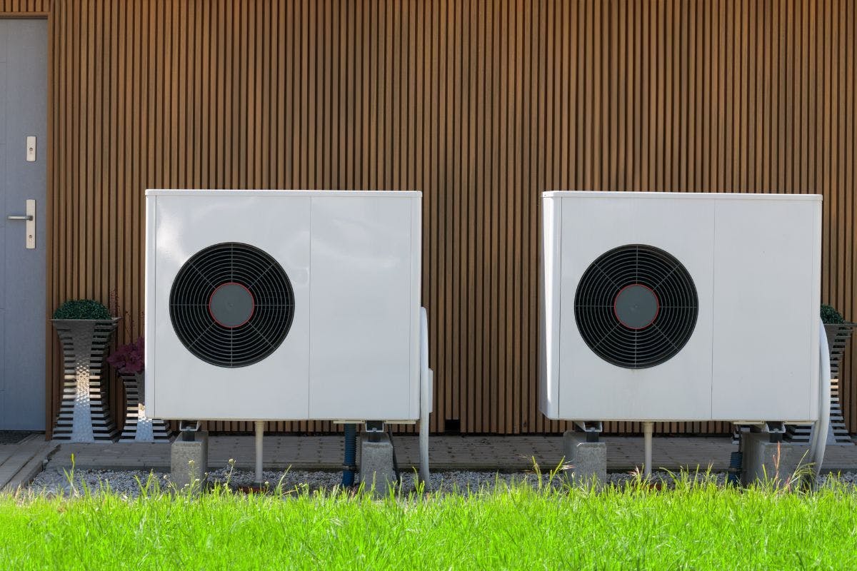 Two exterior heat pump units against a wall.
