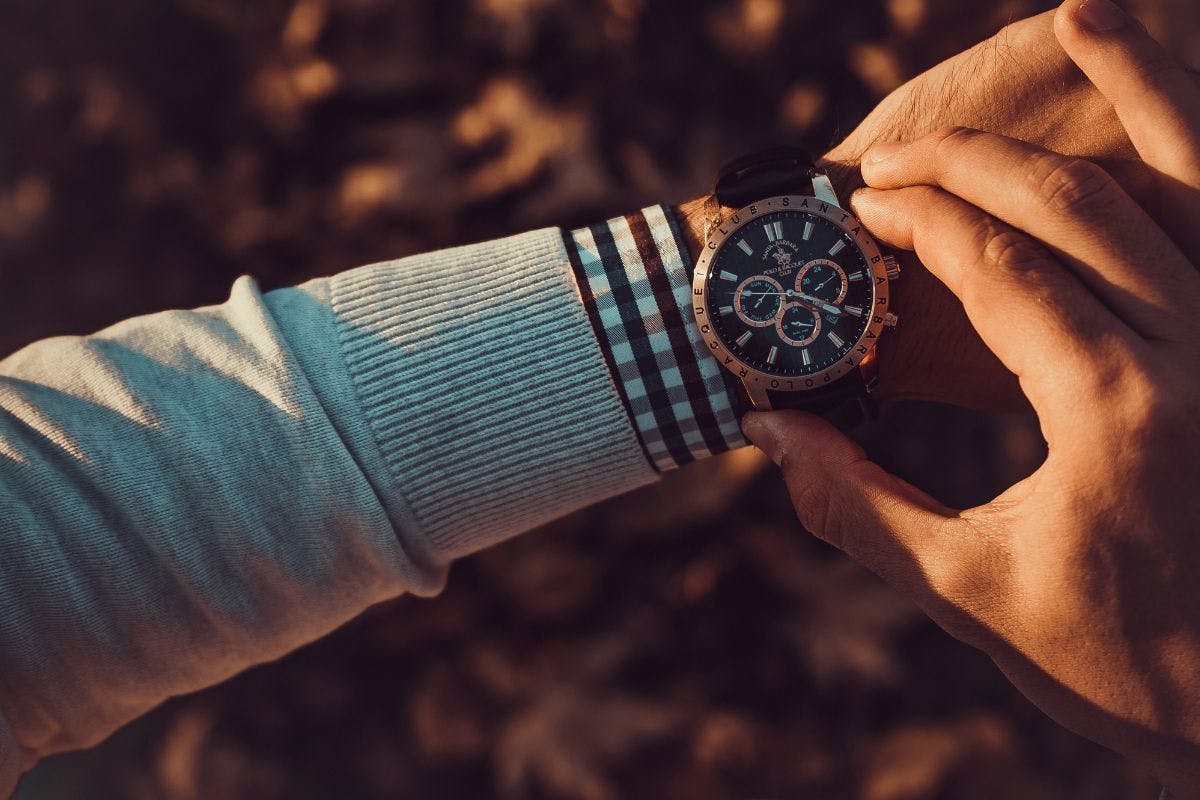 Someone checking a wristwatch at sunset.
