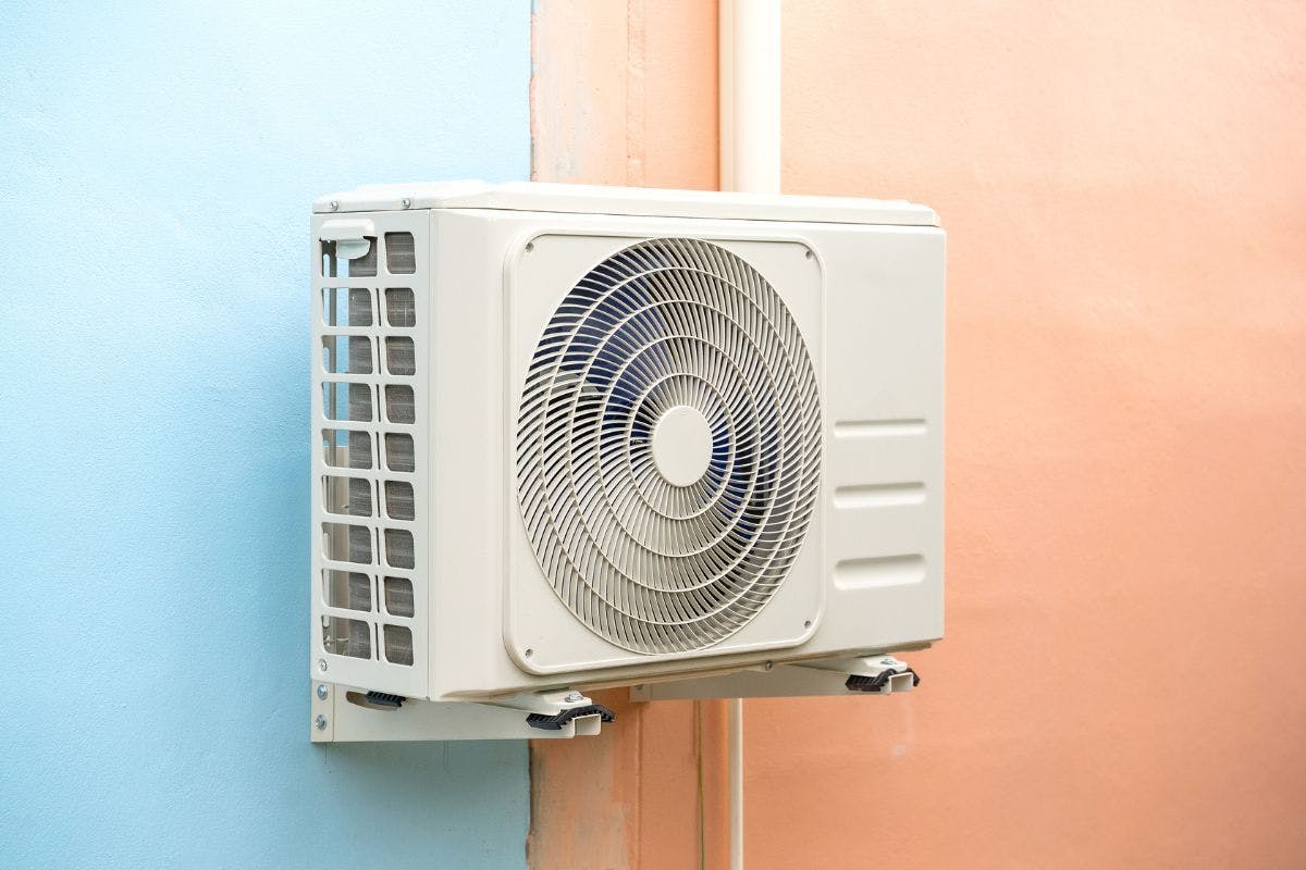 A heat pump mounted on a blue and peach wall.