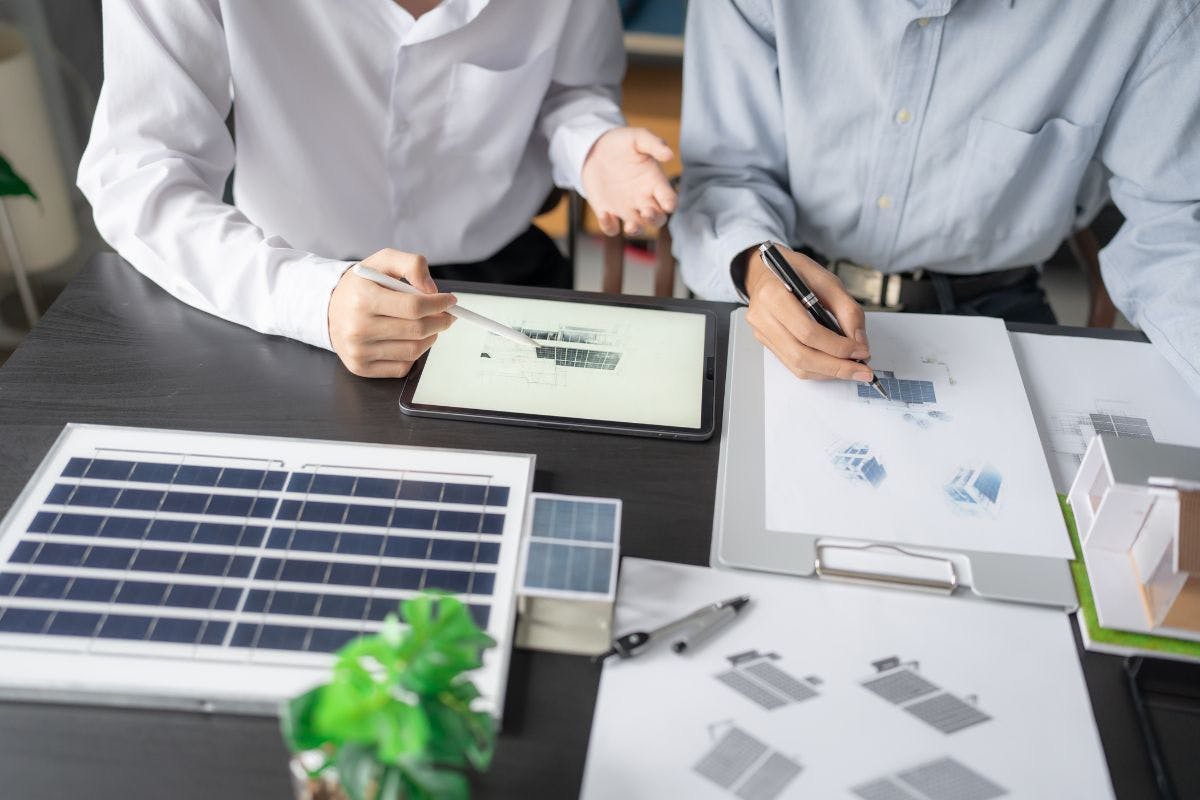 Two people examine plans for a solar installation.