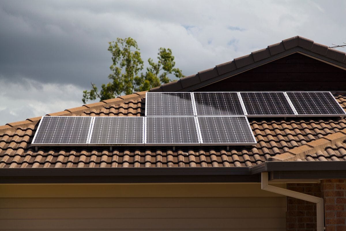 Eight solar panels on the tile roof of a house.
