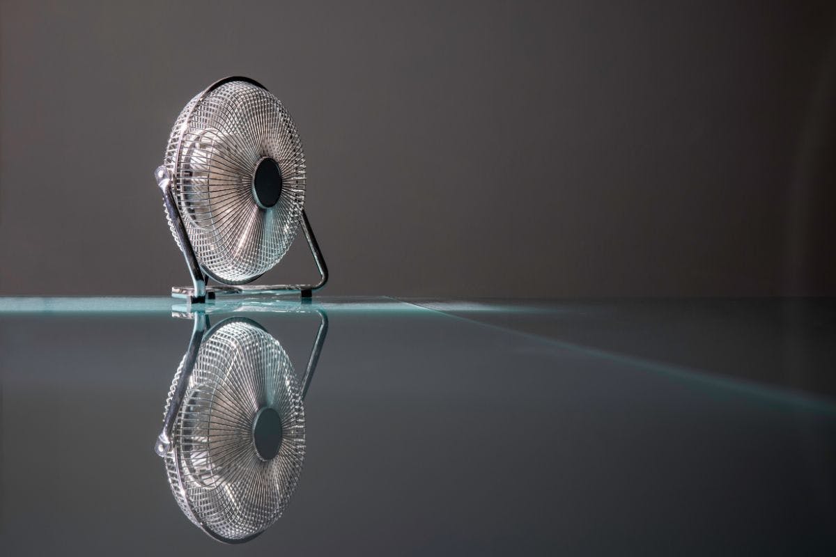 A small fan sitting on a dark reflective surface.