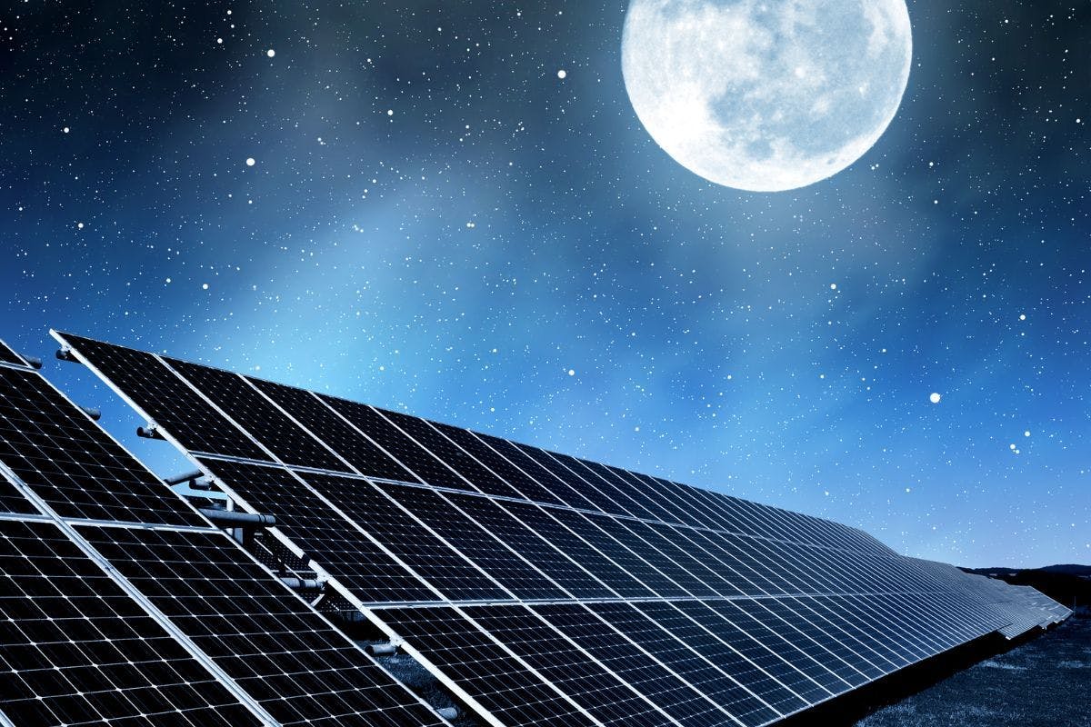 Solar panels at night under a bright full moon.