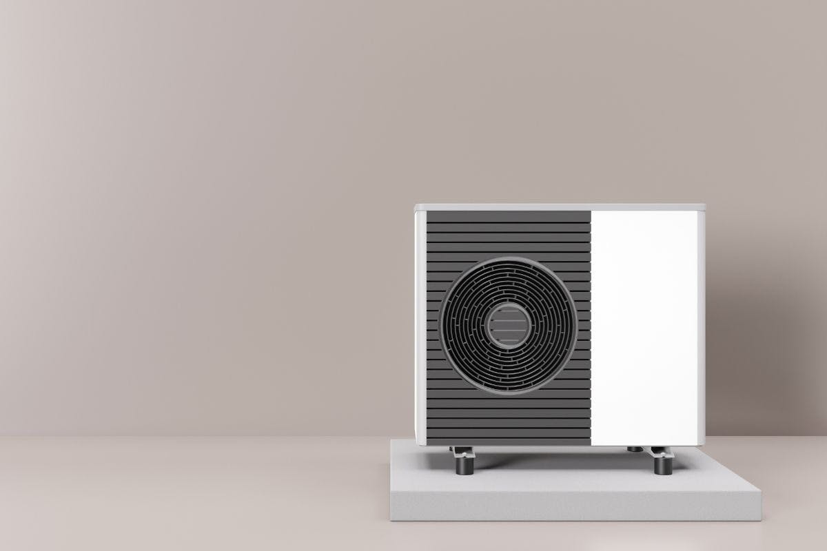 A heat pump against a gray wall.
