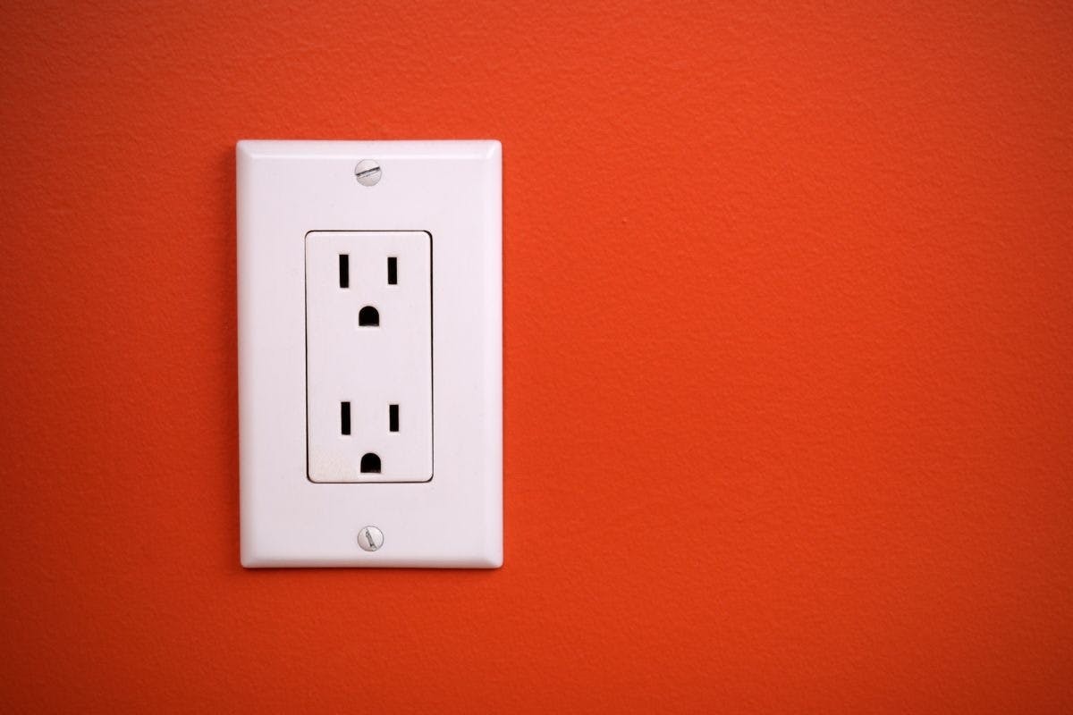 An outlet on an orange wall