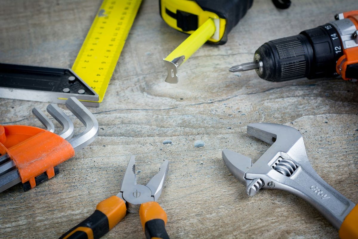 A variety of tools sitting on a wooden surface.