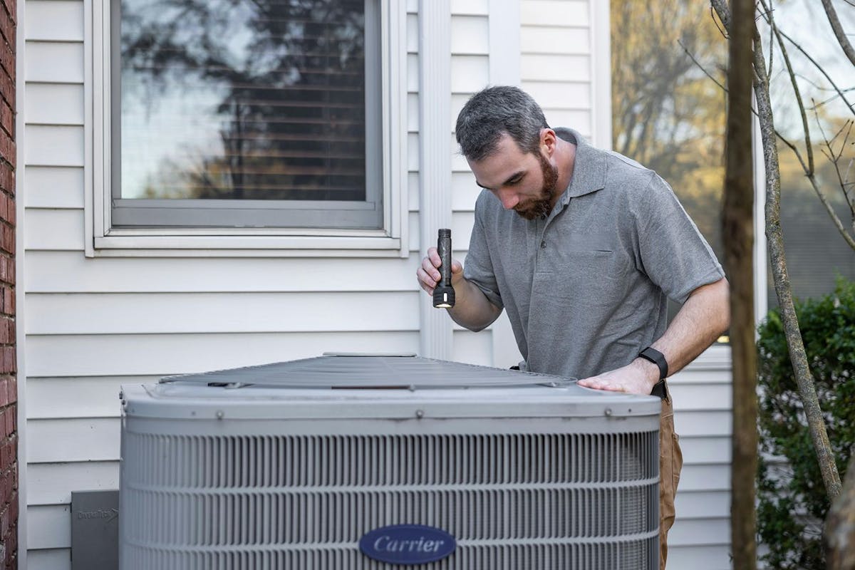 A technician inspects a heat pump.