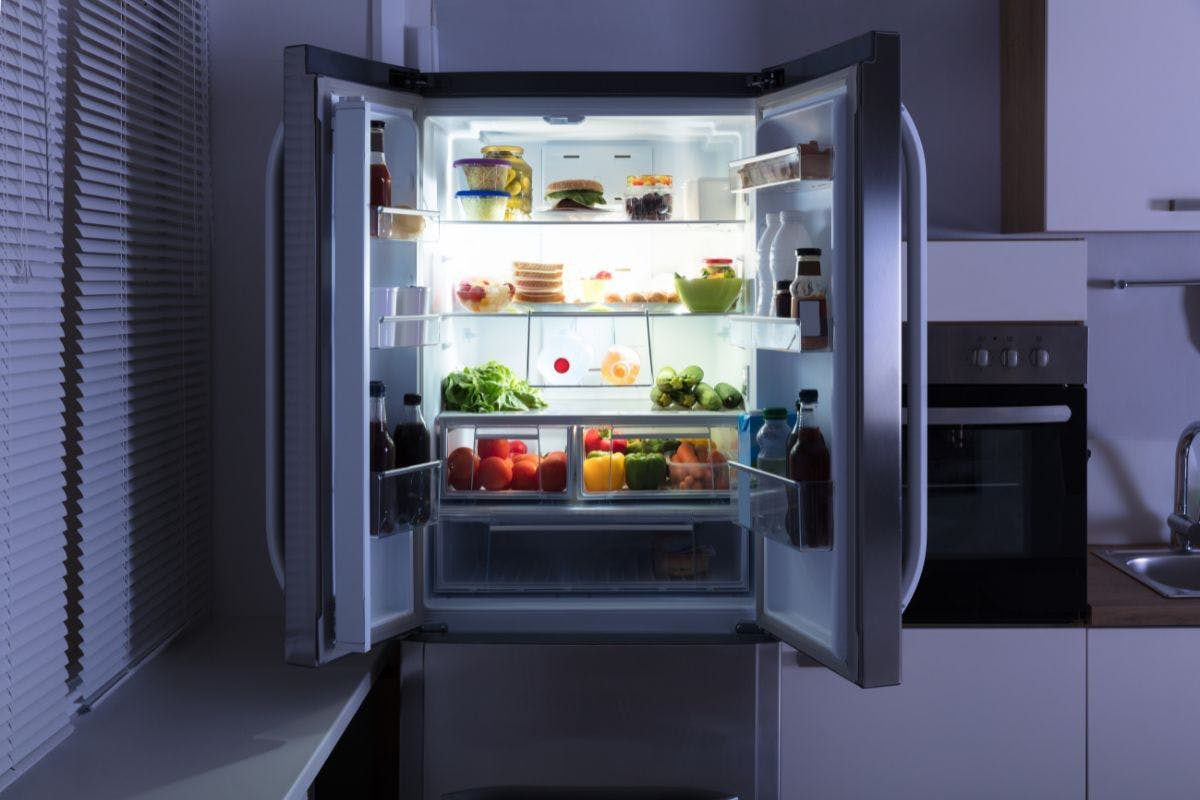 An open refrigerator in a dimly lit kitchen.