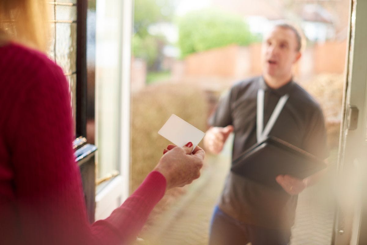 A salesman makes a pitch to a homeowner at the front door.