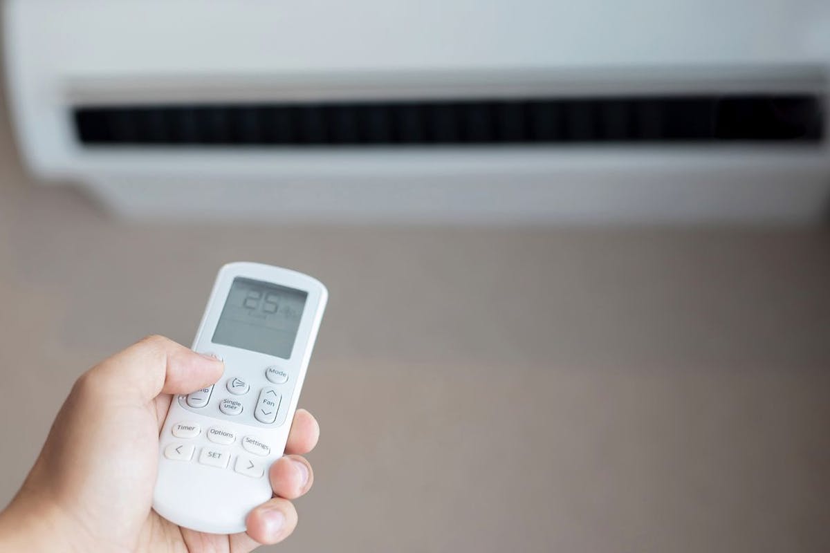 A person points a remote at a mini-split air conditioner or heat pump.