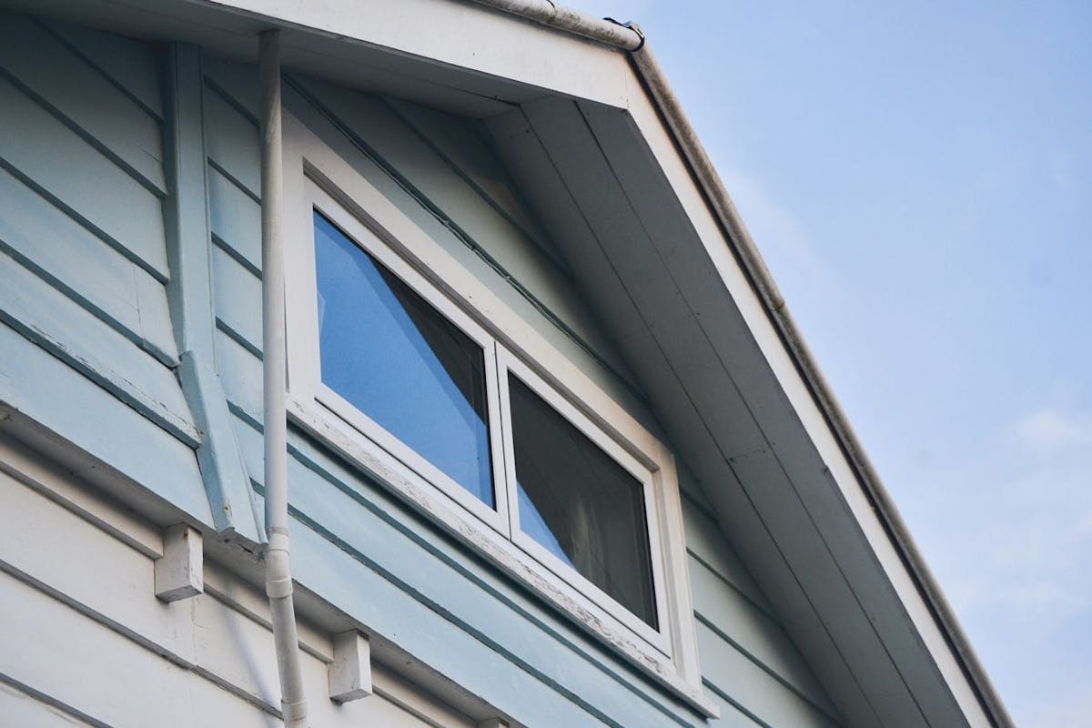 A window in a light blue home's upper level viewed from the outside.