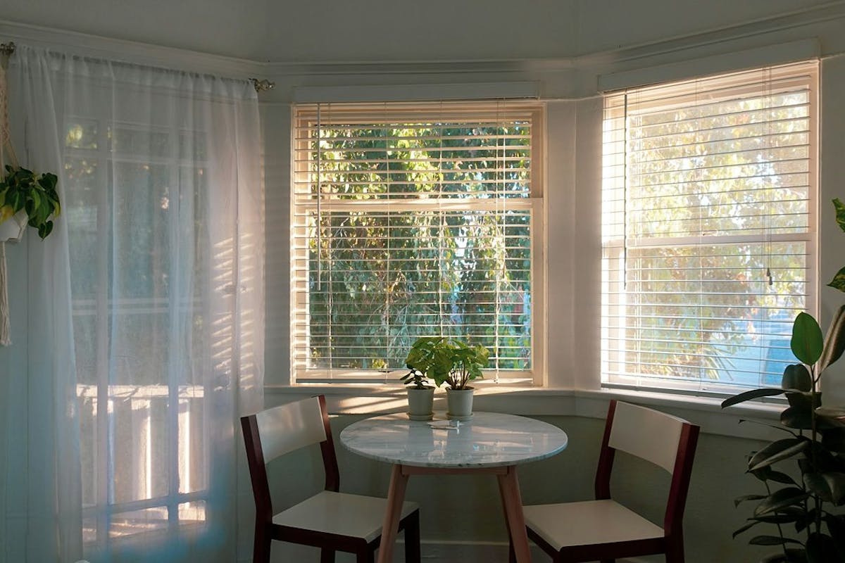 Blinds and curtains in a breakfast nook let in gentle light.