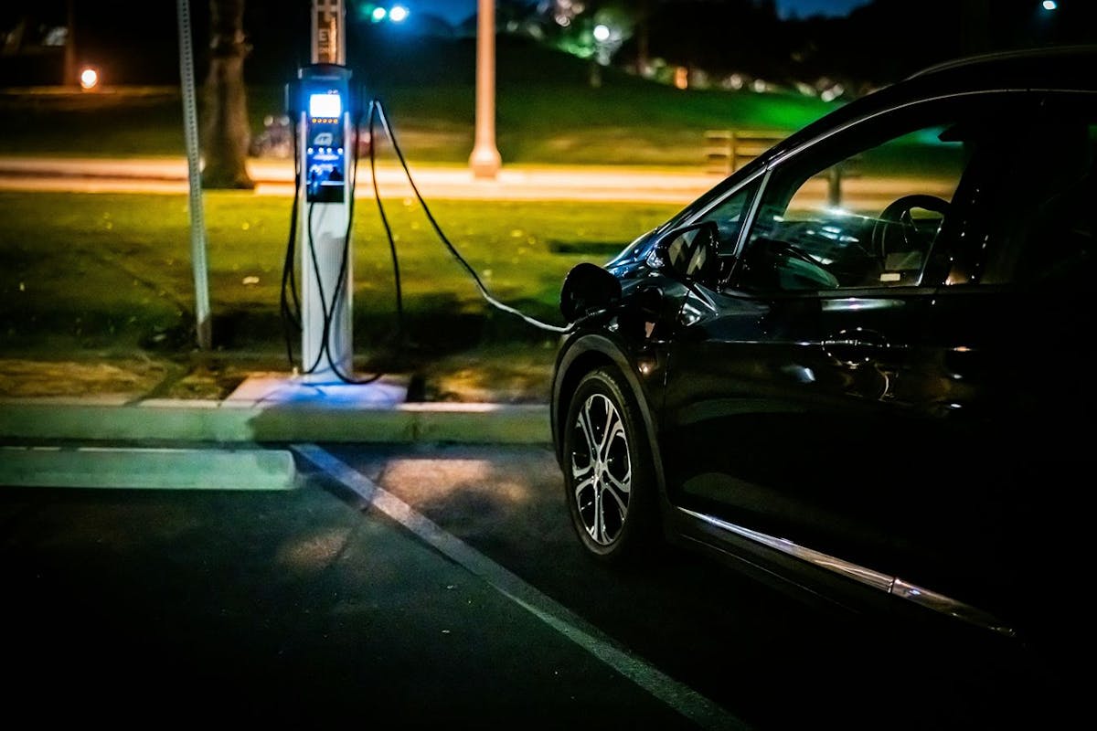 An electric vehicle charging at night in a public location.