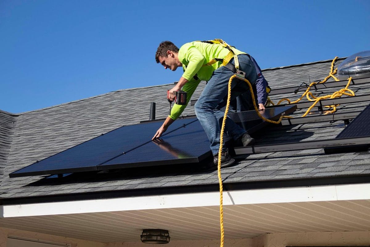 A solar installer puts panels on a roof.
