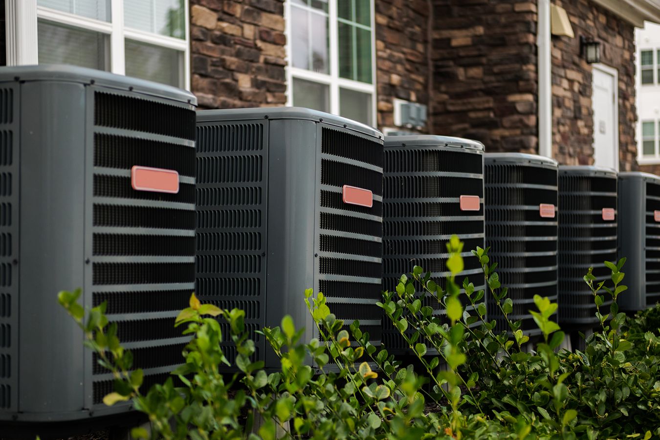 A line of HVAC units installed outside a building.