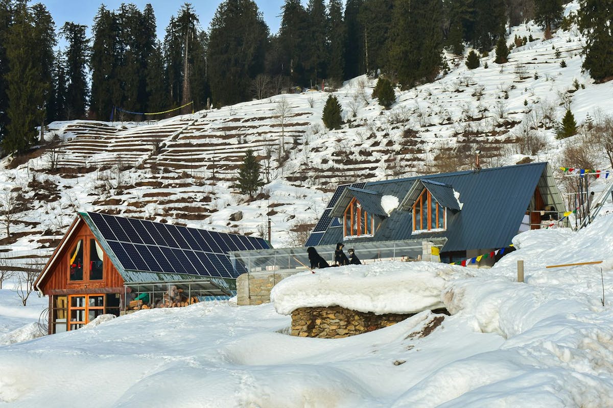 A house with snow-free solar panels in a snowy landscape.