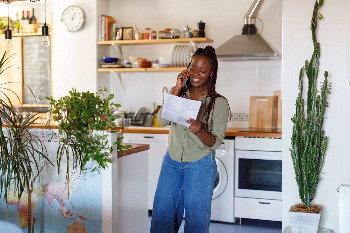 A woman holding an energy bill while talking on the phone.