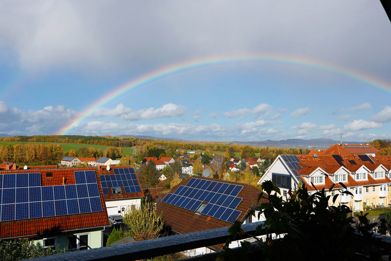 A rainbow over homes with solar panels on their roofs.