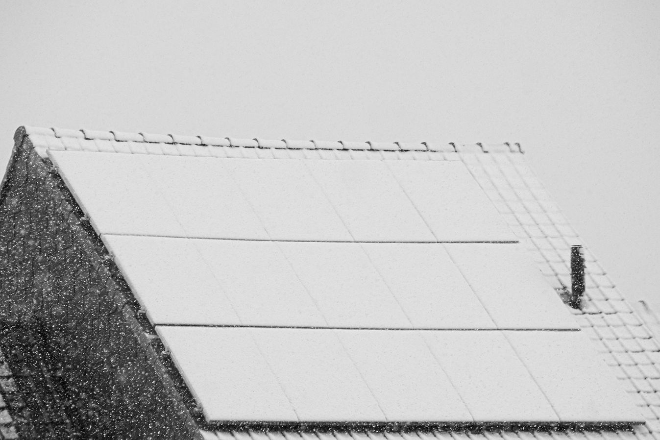 Snow, one of the potential reasons for lower solar generation in the winter, on solar panels on a large roof.