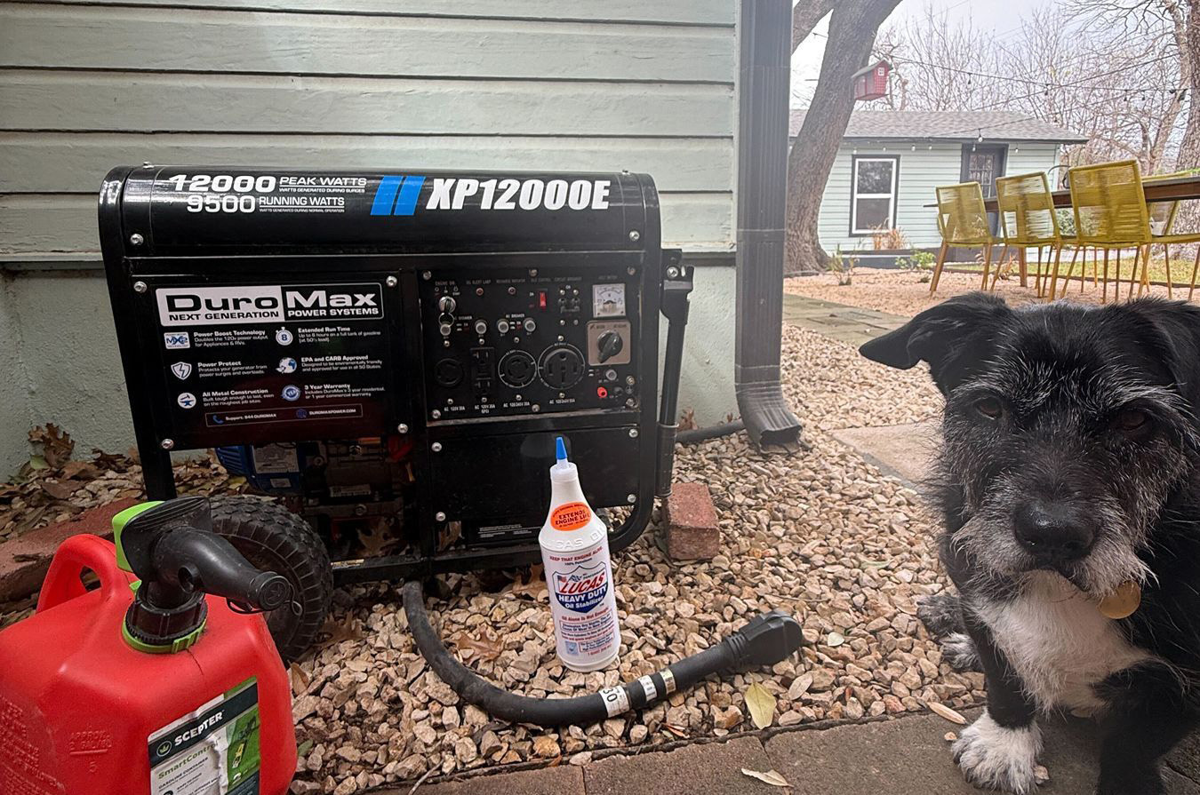 A small dog sitting next to a portable generator.