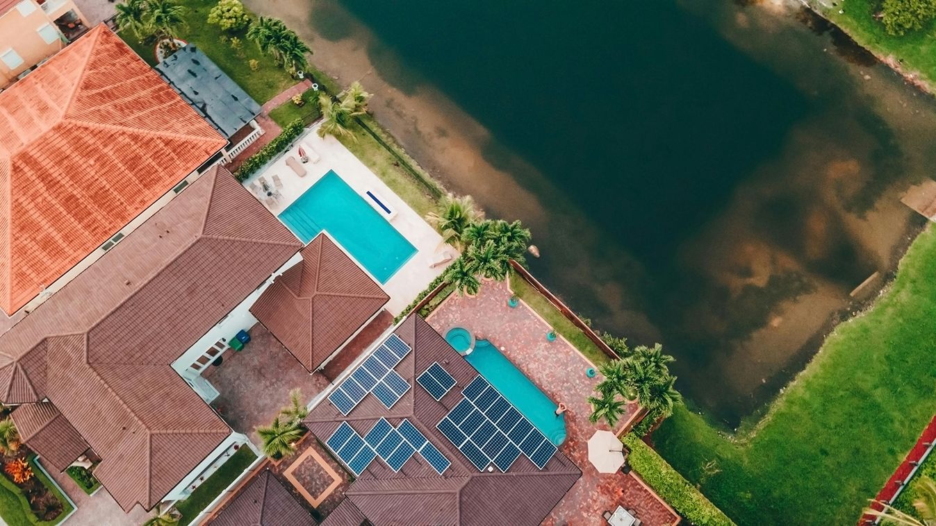 Solar panels on a roof with a swimming pool and palm trees.