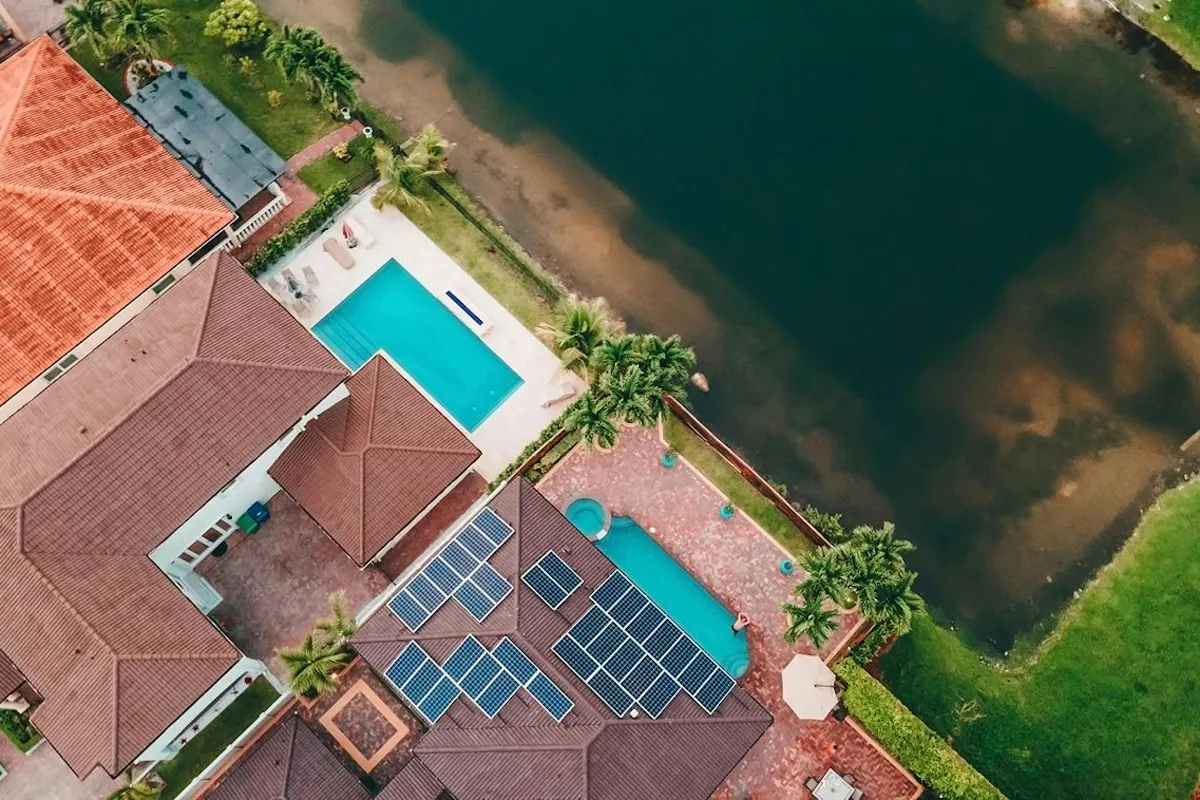 Solar panels on a roof with a swimming pool and palm trees.
