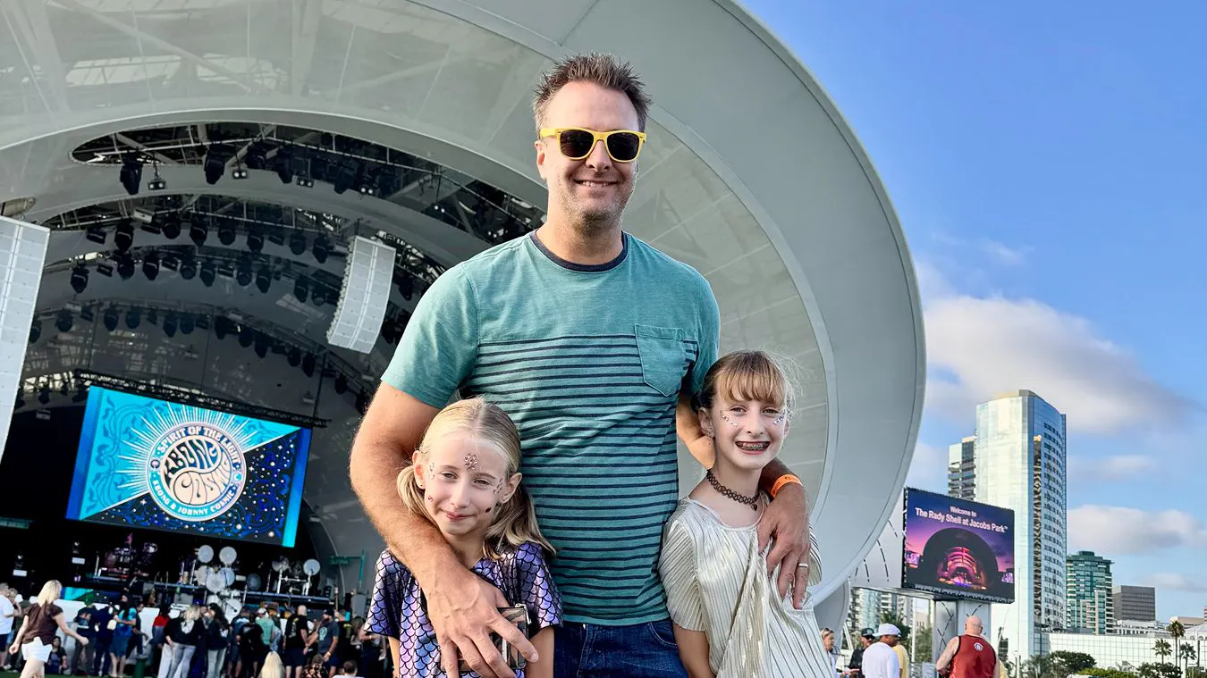 Troy with his daughters at an outdoor concert.
