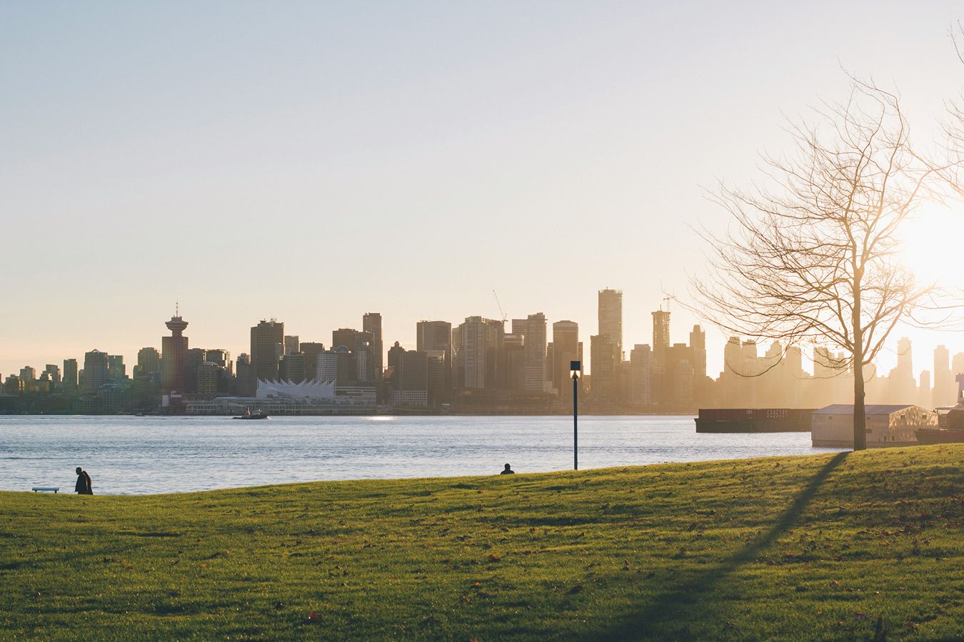The sun rises over a city park with a lake.