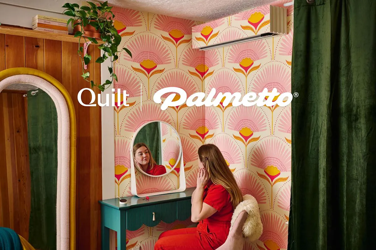 A woman looking in a mirror beneath a Quilt heat pump.