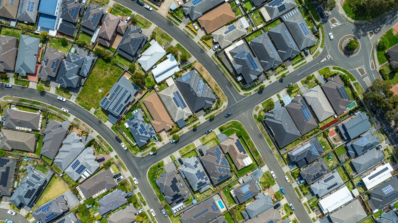 Solar panels on roofs in a neighborhood seen from above.