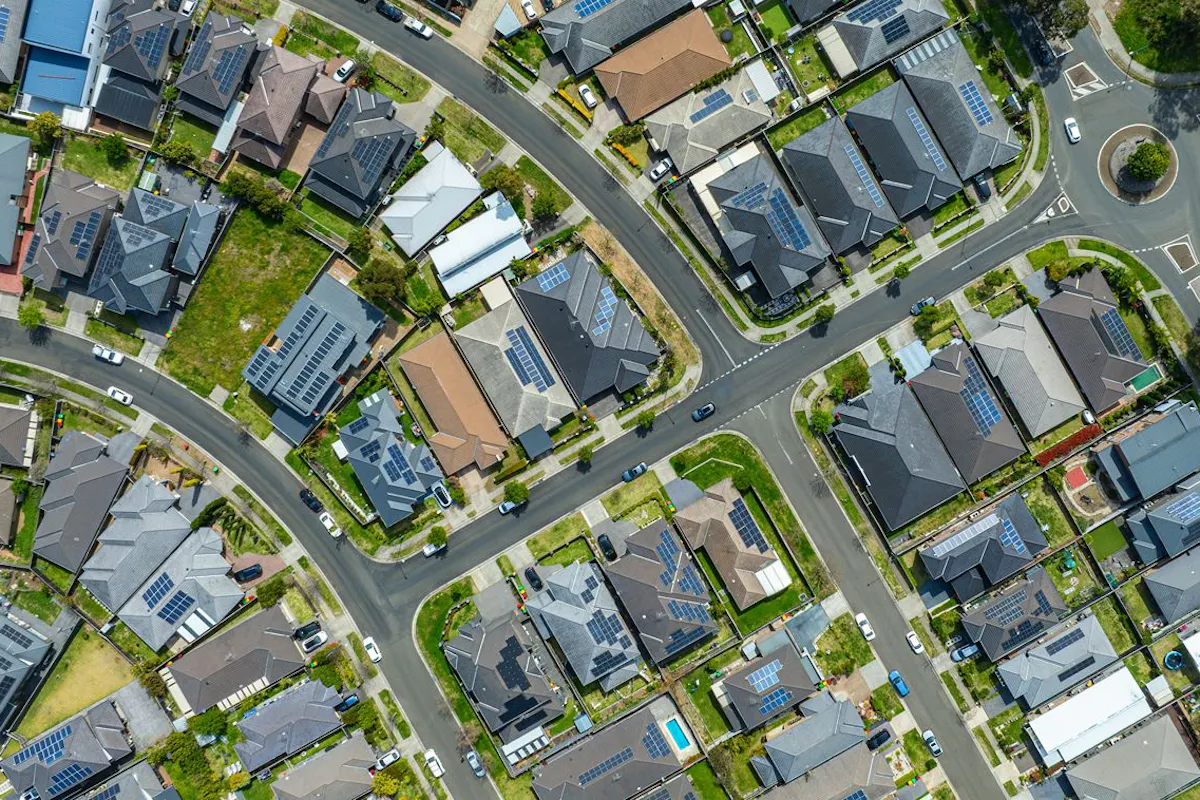 Solar panels on roofs in a neighborhood seen from above.