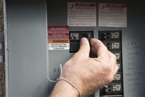 Hand turning the PV Solar Breaker in the main electrical panel to the OFF position.