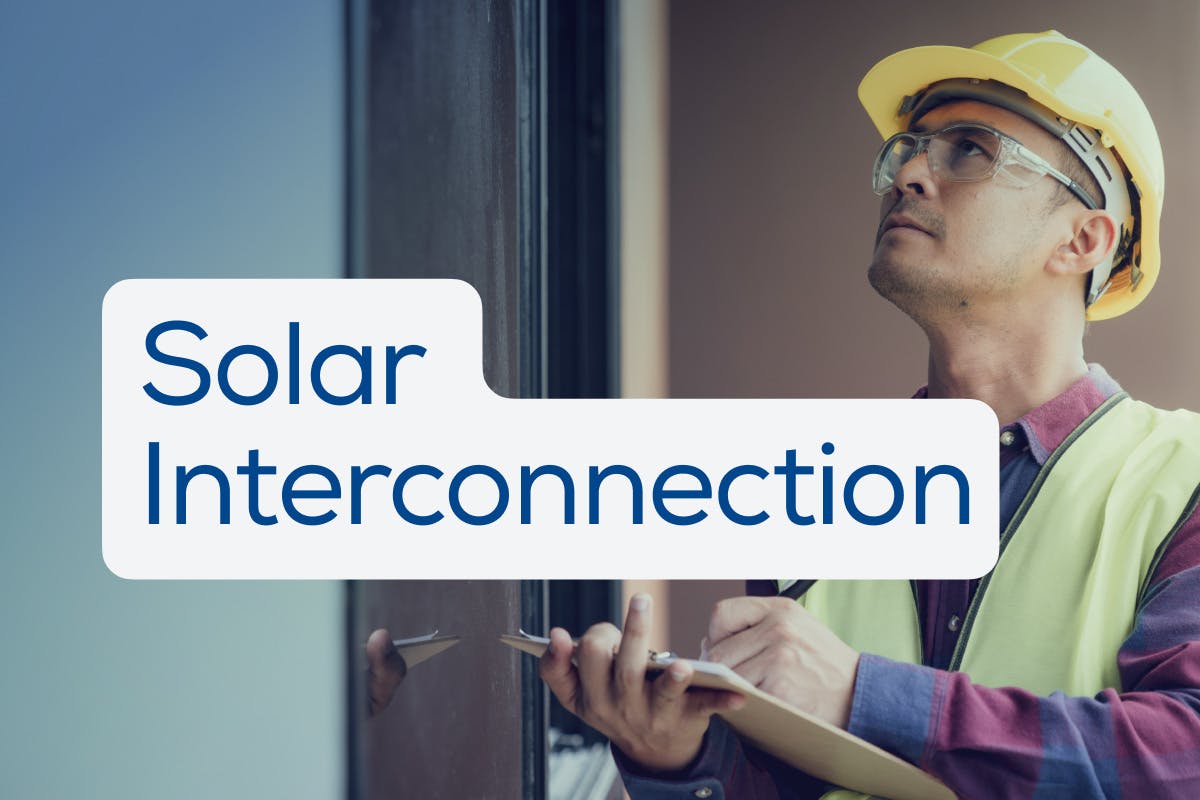 Utility inspector in yellow hard hat, yellow vest, and red-and-blue plaid shirt inspects a home solar panel installation with the words "Solar Interconnection" on top, as a homeowner applies for Permission To Operate.