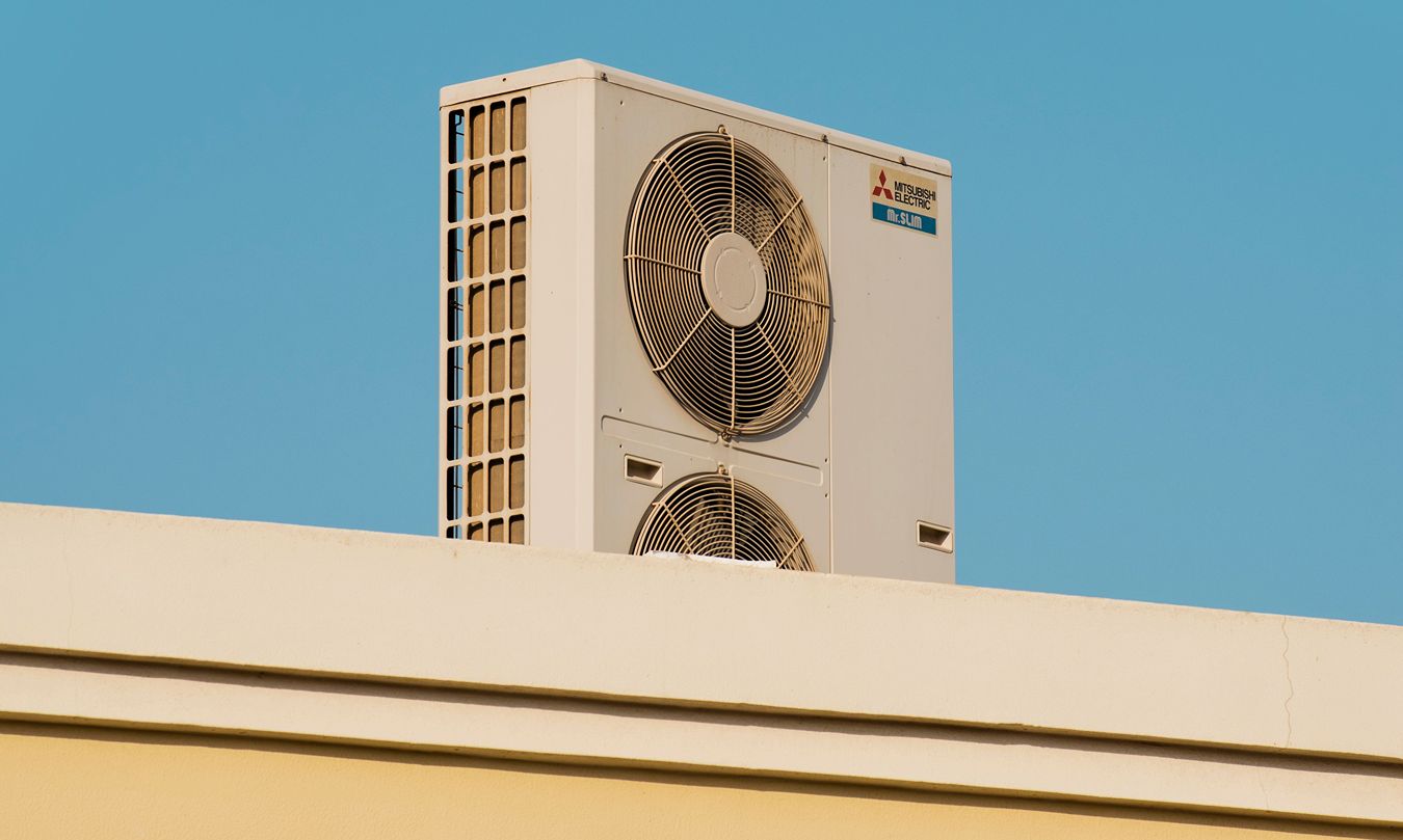 A heat pump on a roof in front of a blue sky.