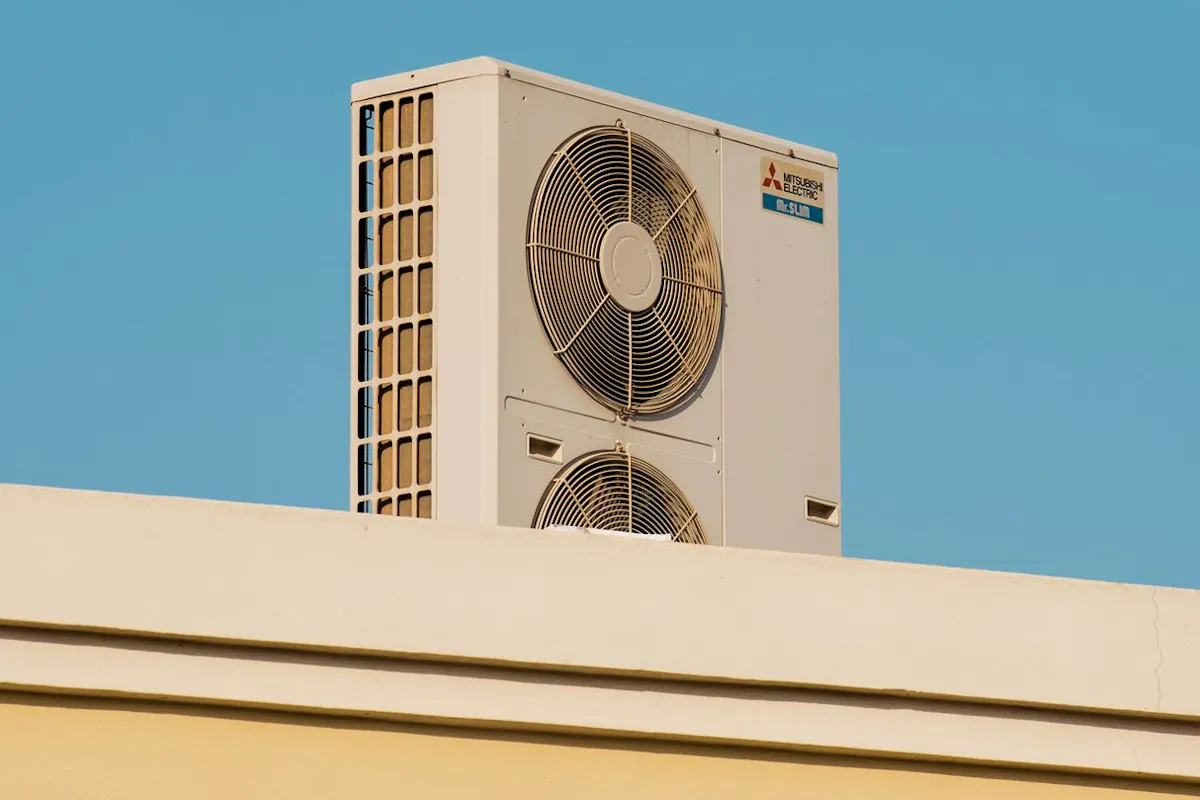 A heat pump on a roof in front of a blue sky.