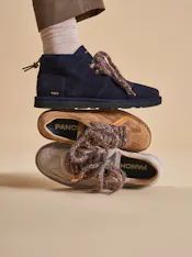 Un piede si appoggia su altre due scarpe.