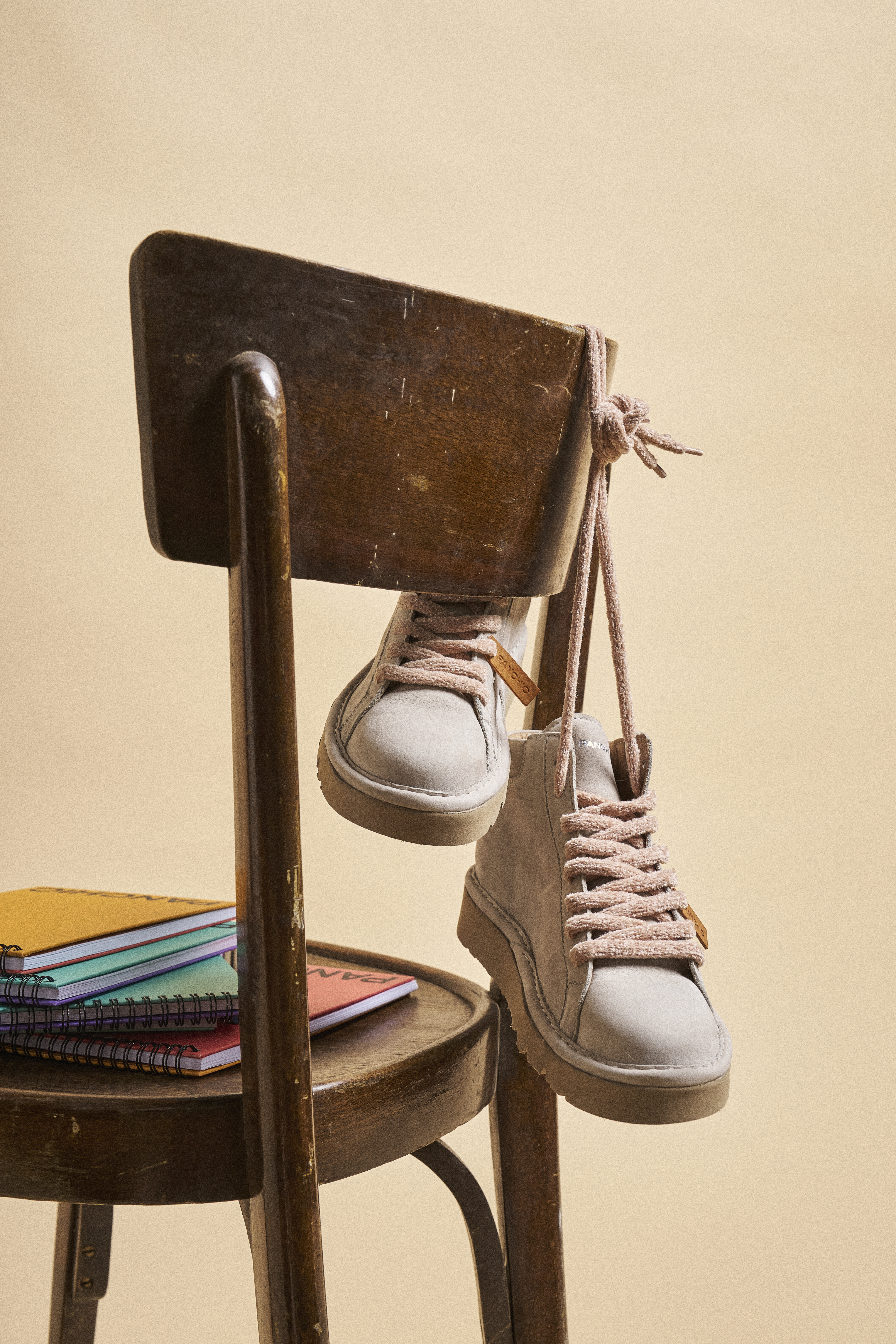 A pair of P007 in dove grey is hanging from the back of a chair.