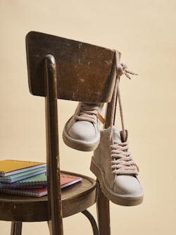 A pair of P007 in dove grey is hanging from the back of a chair.
