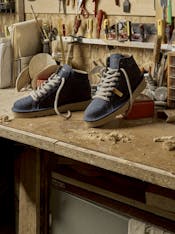 On a carpenter desk sits a pair of blue P007 ankle boots.