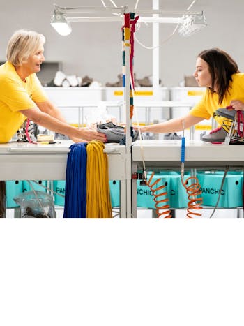 Two women are working together to make a shoe.