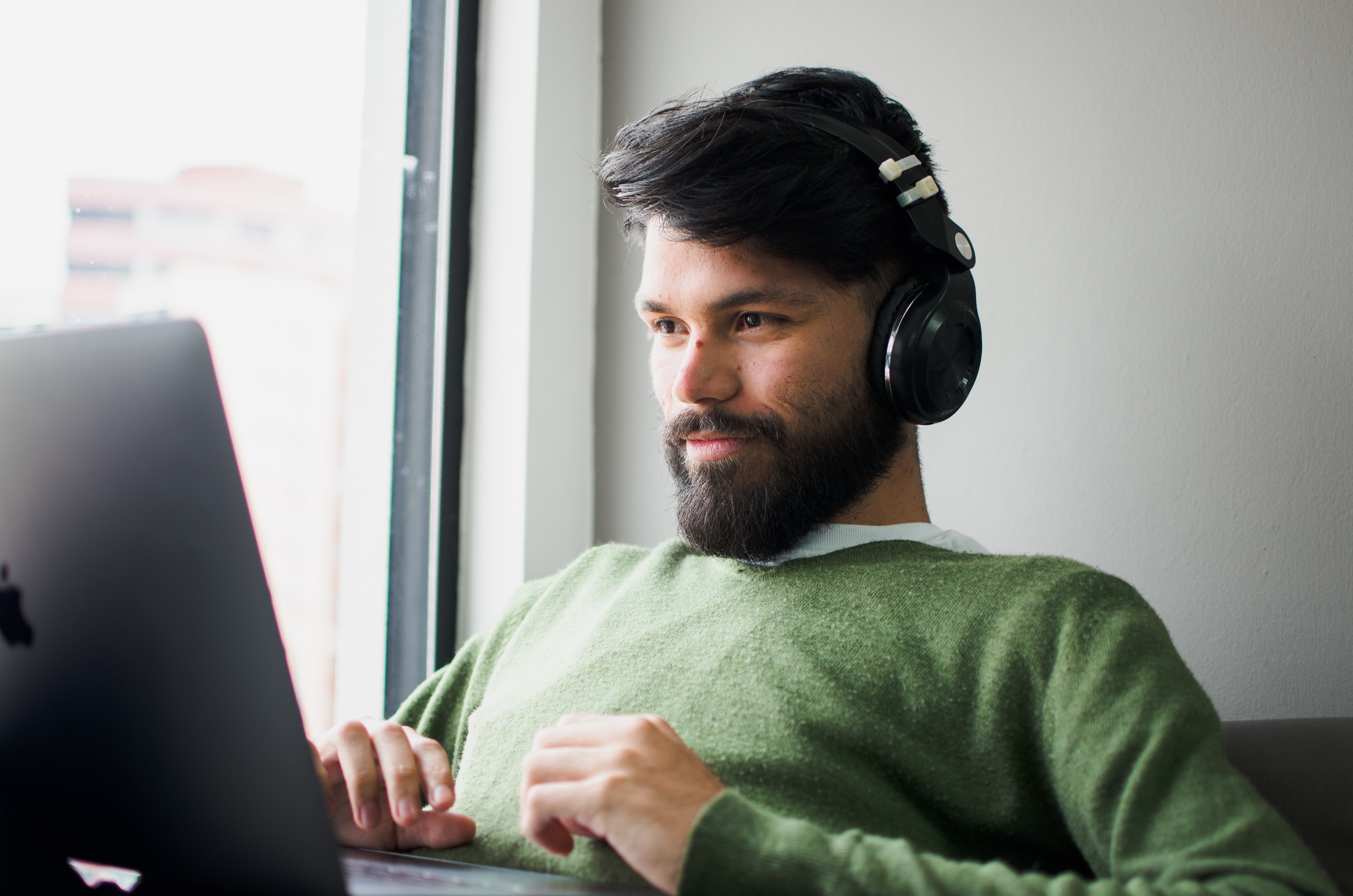 Photo of a man looking at a computer with headphones