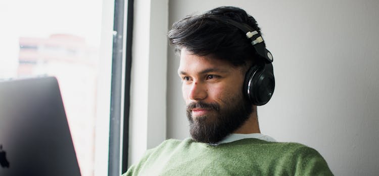 Foto de hombre mirando el computador con audífonos