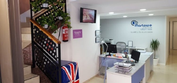 Recepción de Marlowe Centre Idiomas | Salón blanco con mesas blancas y una escaleras a la izquierda.
