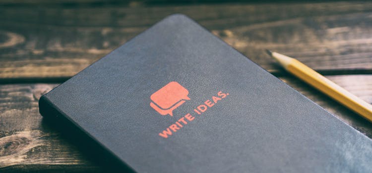 libreta de notas color negro cno lapiz amarillo sobre mesa de madera