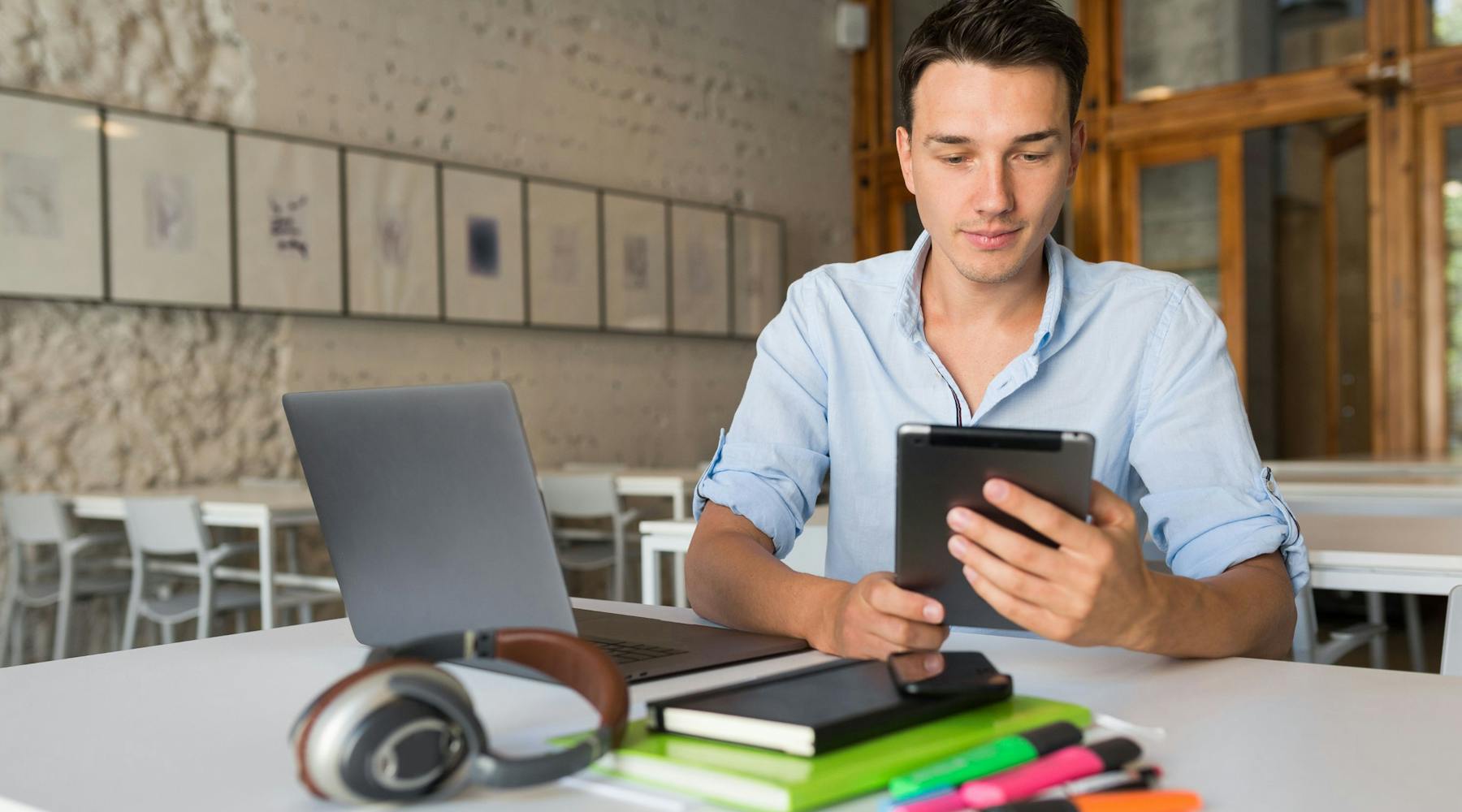 Junge Mann, der mit PC und Handy an einem Tisch lernt