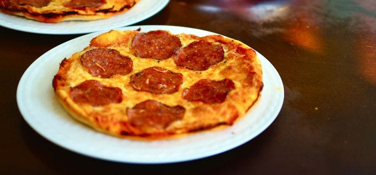 foto de una piezza de pepperoni circular sobre un plato blanco