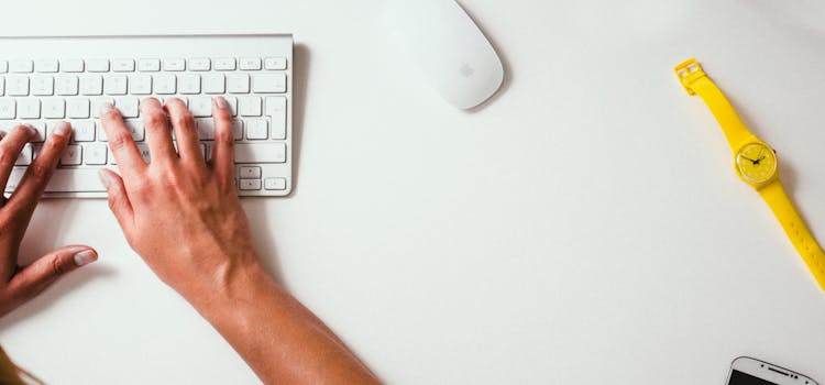 Hands typing on white keyboard